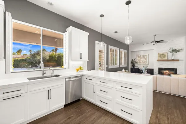 a large white kitchen with a large window and stainless steel appliances