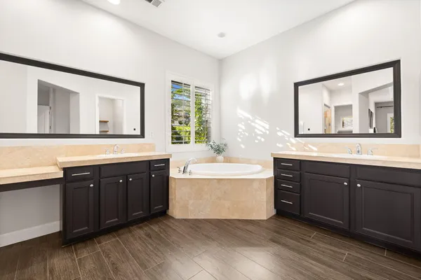 a spacious bathroom with a tub double sink and mirror