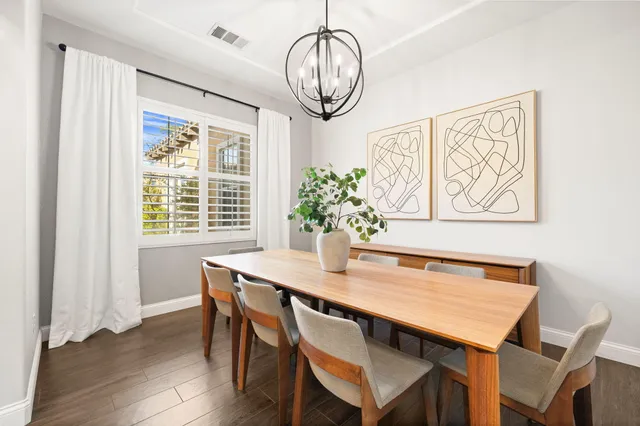 a dining room with wooden floor a chandelier a wooden table and chairs