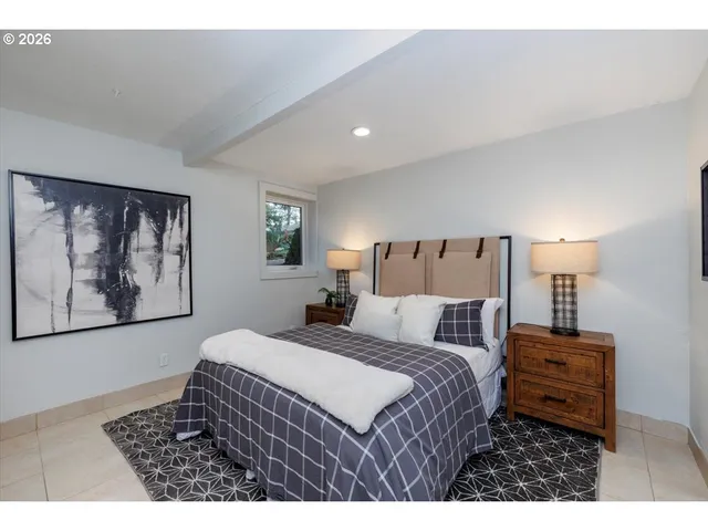 a bedroom with a bed a painting on the wall and a lamp