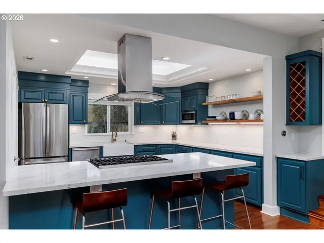 a kitchen with stainless steel appliances kitchen island granite countertop a table chairs sink and cabinets