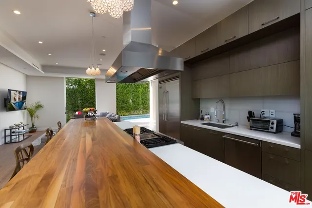 a large kitchen with kitchen island a large counter top space a sink stainless steel appliances and cabinets