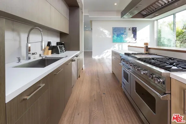 a kitchen with sink a stove and wooden floor