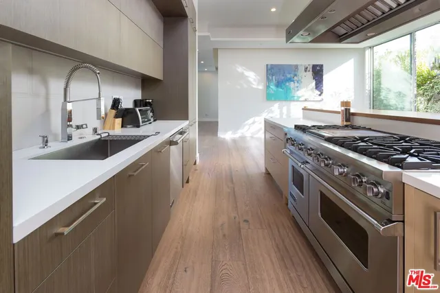 a kitchen with sink a stove and wooden floor