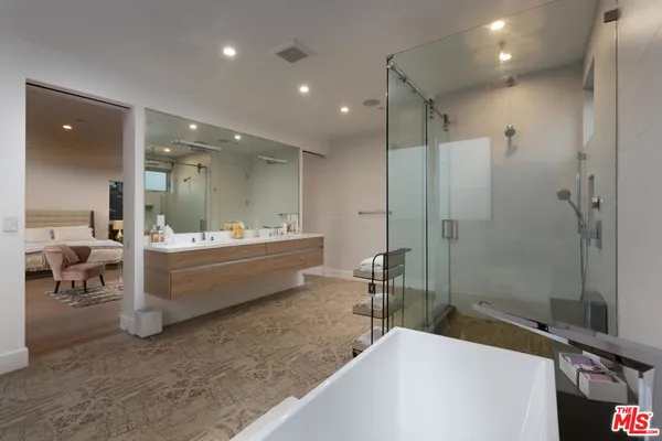 a bathroom with a double vanity sink a toilet a mirror and shower