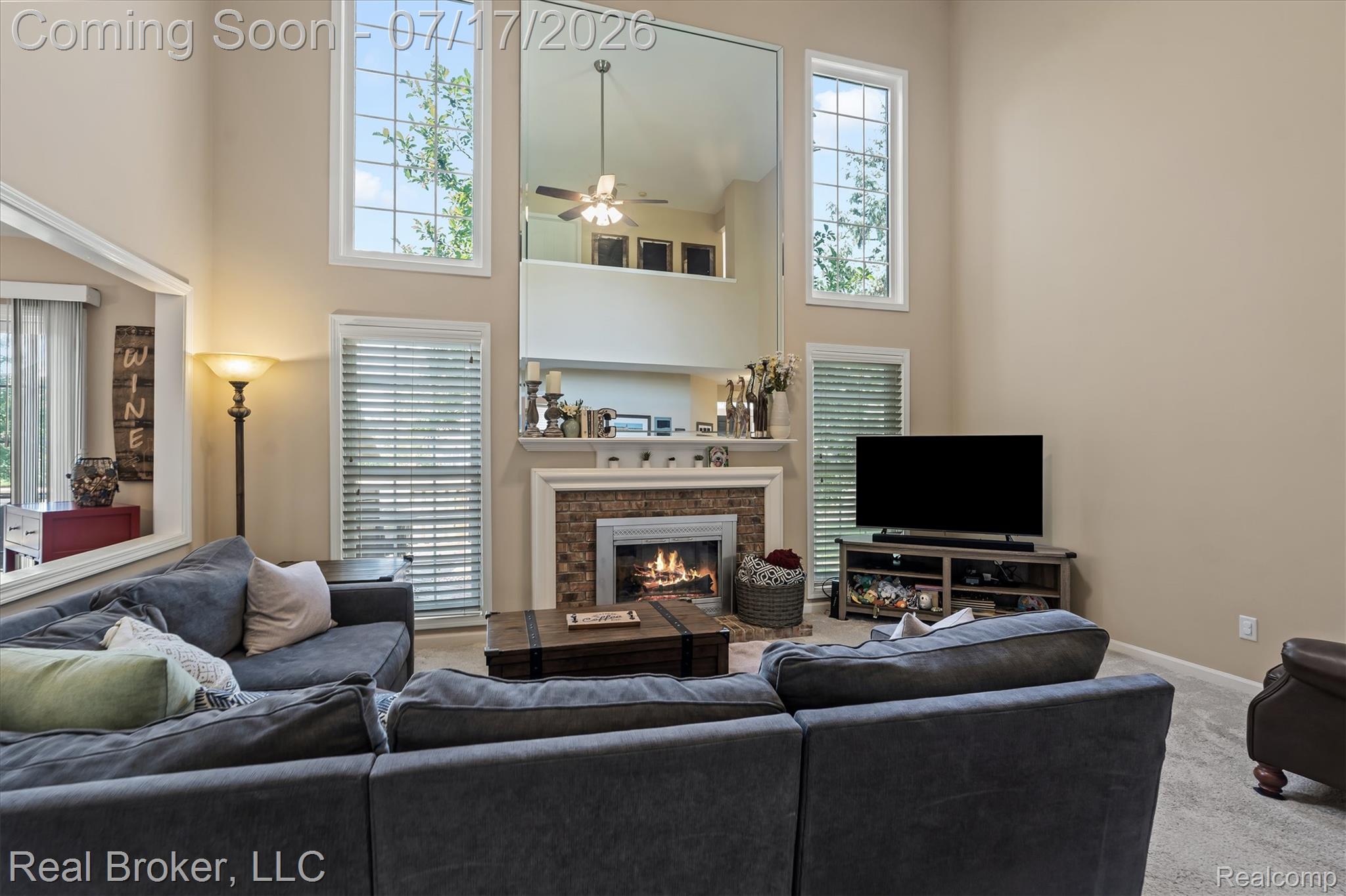 45192 Thornhill Road Canton, MI 48188 - Photo 4 of 34 Living area featuring a two-story ceiling, a stone-faced fireplace with a mantel, and an array of tall vertical windows