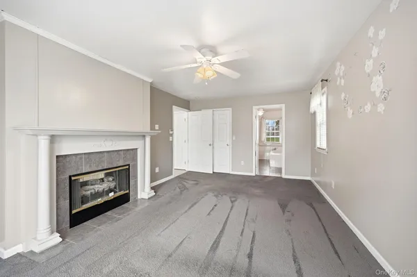 a view of a livingroom with a fireplace a ceiling fan and wooden floor