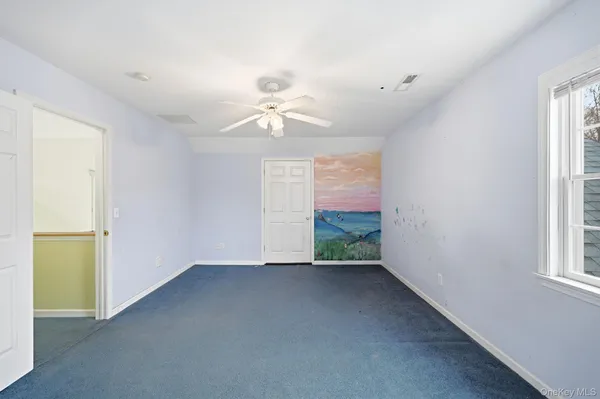 an empty room with windows and fan