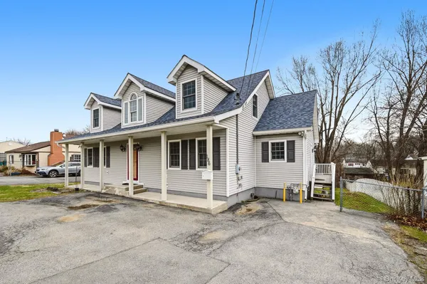 a view of a white house with large windows next to a road
