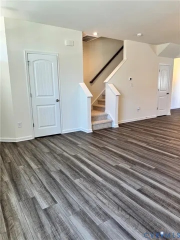 a view of a livingroom with wooden floor and stairs