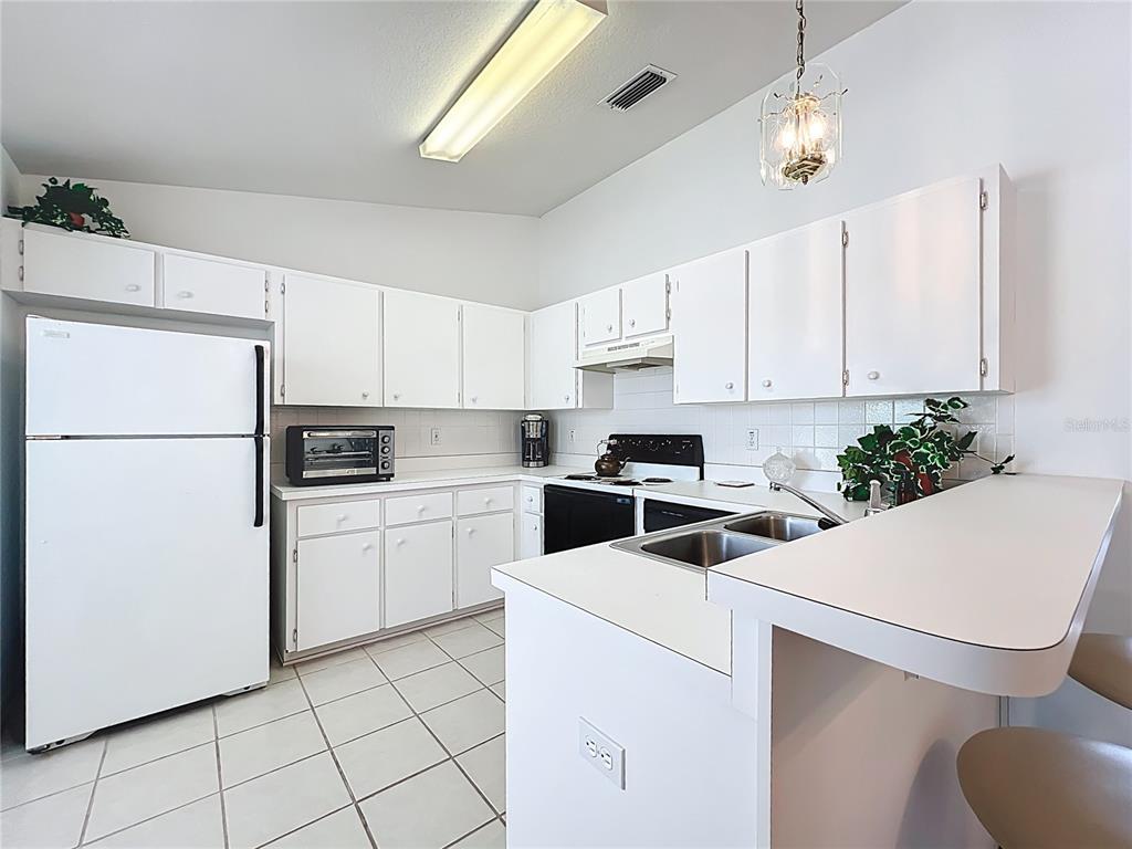 22163 Southwest Edgewater Boulevard Dunnellon, FL 34431 - Photo 49 of 78 a kitchen with a white refrigerator and white cabinets