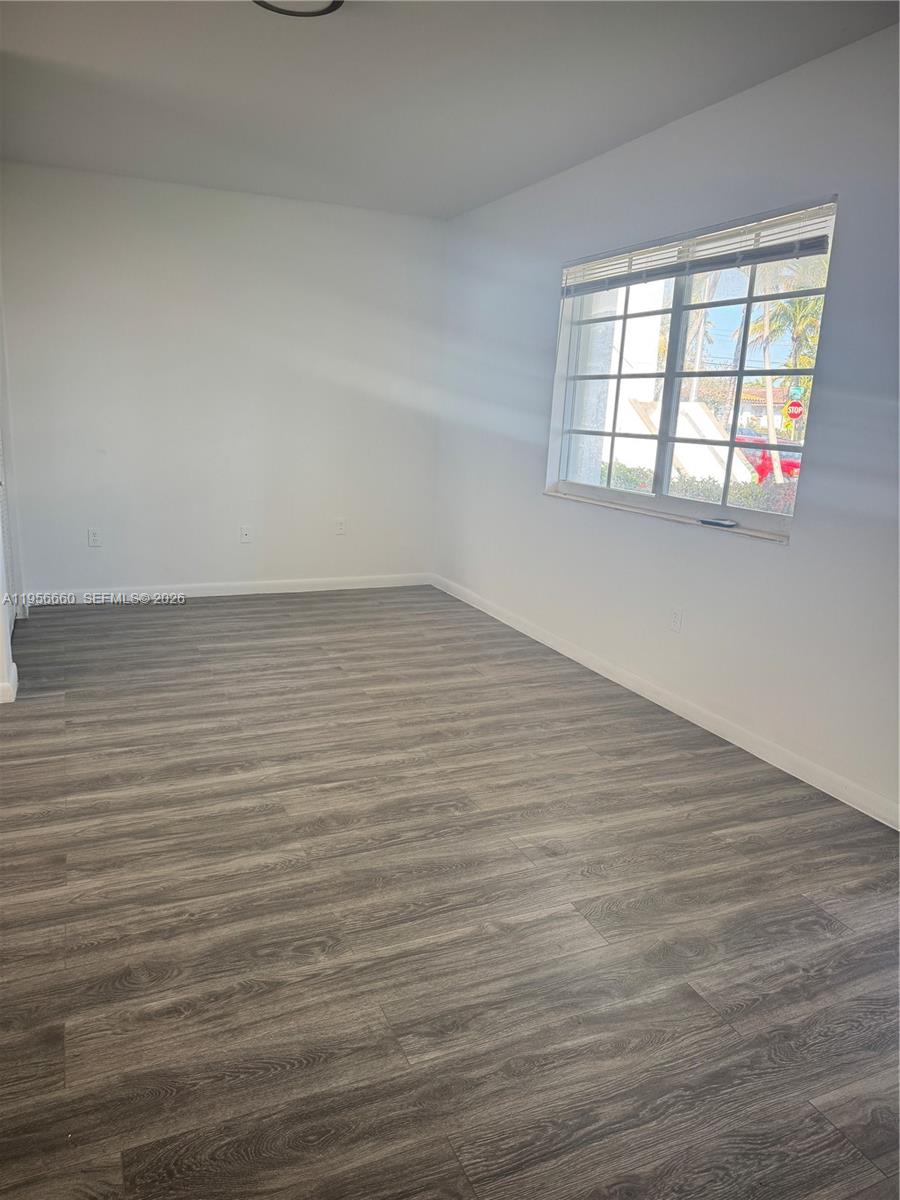 7130 Rue Versailles Drive, Unit 4 Miami Beach, FL 33141 - Photo 11 of 12 wooden floor in an empty room with a window