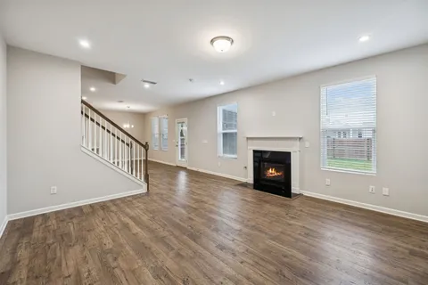 a view of an empty room with wooden floor fireplace and a window