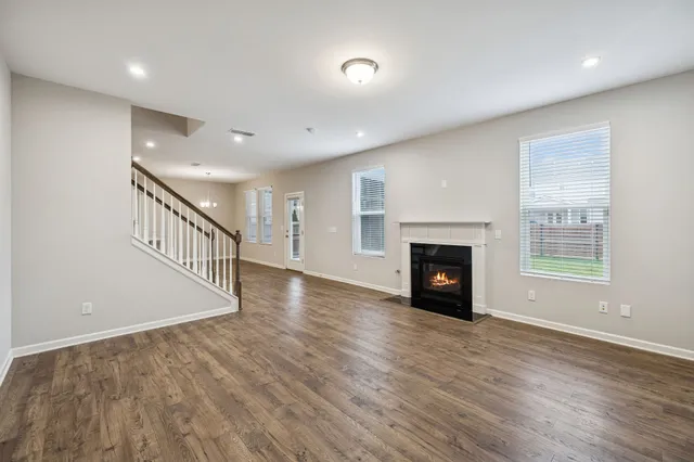a view of an empty room with wooden floor fireplace and a window