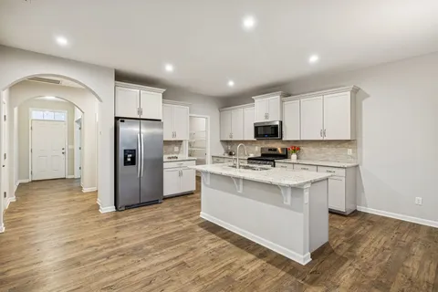 a kitchen with stainless steel appliances granite countertop a refrigerator a stove a sink and a microwave