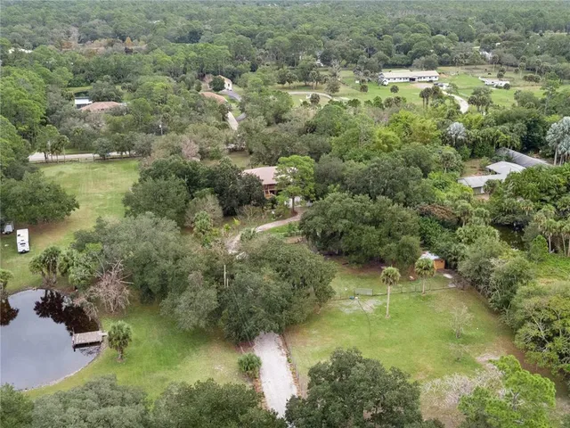 an aerial view of residential house with outdoor space and trees all around
