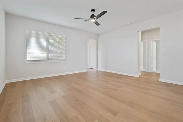 an empty room with wooden floor and stainless steel appliances