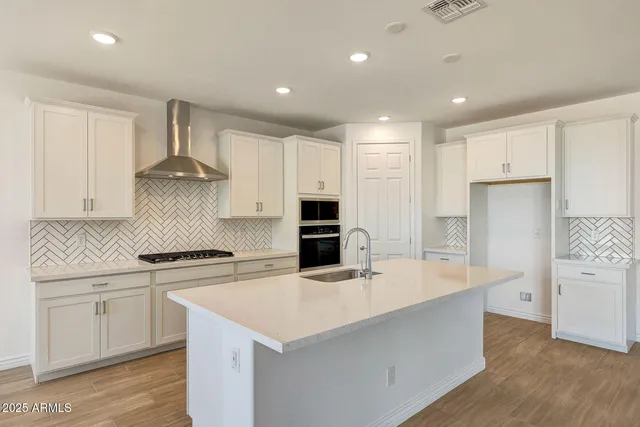 a kitchen with a sink a stove a refrigerator and white cabinets