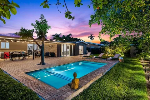 a view of a house with swimming pool lawn chairs and a fire pit