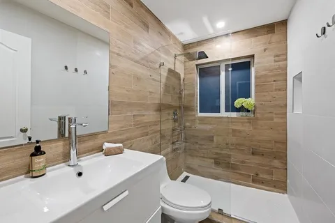 a bathroom with a bathtub shower sink mirror and toilet