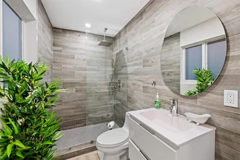 a bathroom with a sink a toilet a mirror and shower