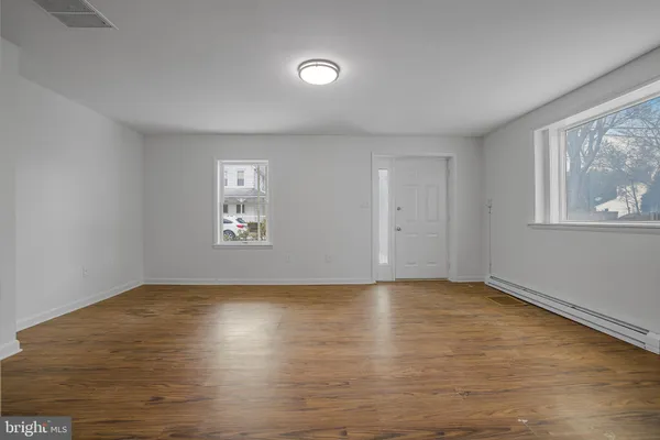 an empty room with wooden floor and windows