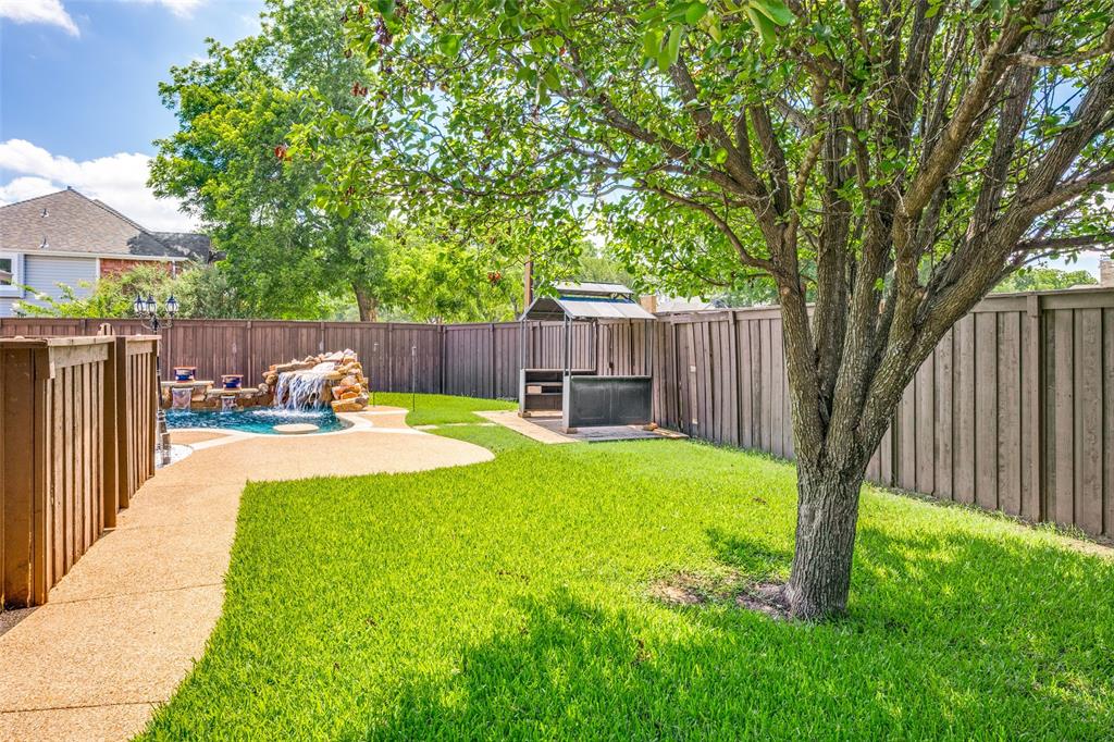 2100 Los Rios Boulevard Plano, TX 75074 - Photo 25 of 25 Backyard oasis featuring a swimming pool with rock waterfall, concrete patio, a built-in outdoor cooking station, and a privacy fence