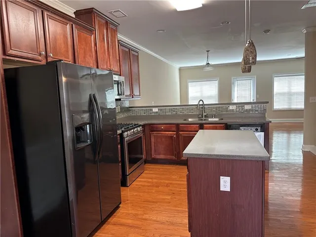 a kitchen with stainless steel appliances granite countertop a refrigerator a sink a stove and wooden cabinets