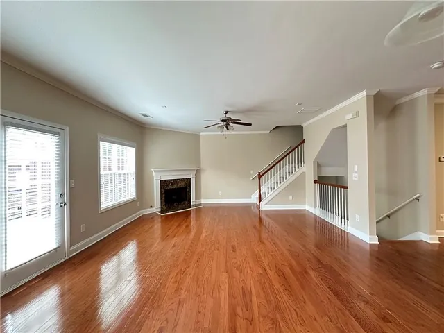 an empty room with wooden floor fireplace and windows