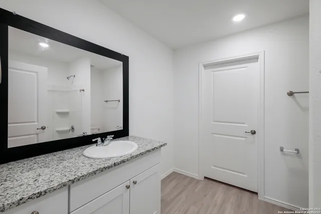 a bathroom with a granite countertop sink and a mirror