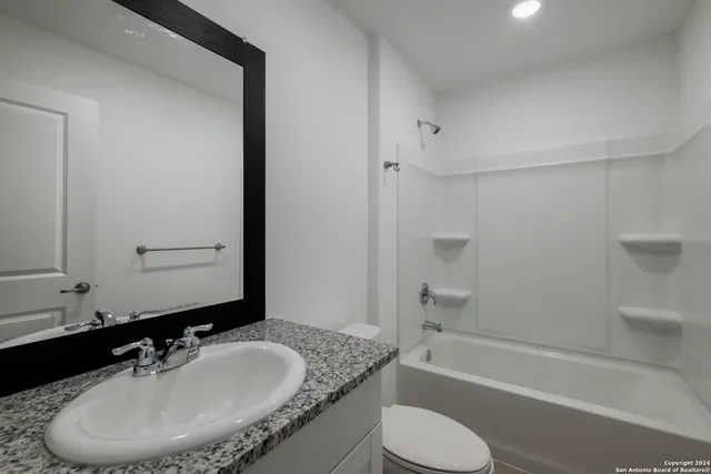 a bathroom with a granite countertop sink toilet and shower
