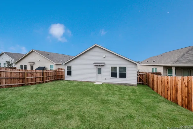 a view of a house with a yard and fence