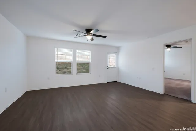 a view of an empty room with a window and wooden floor