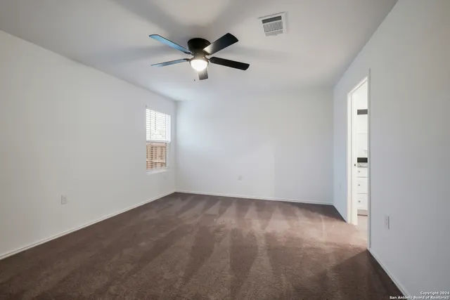 an empty room with windows and fan