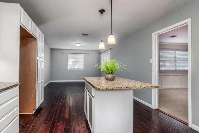 a hallway with granite countertop kitchen island a stove and a wooden floors