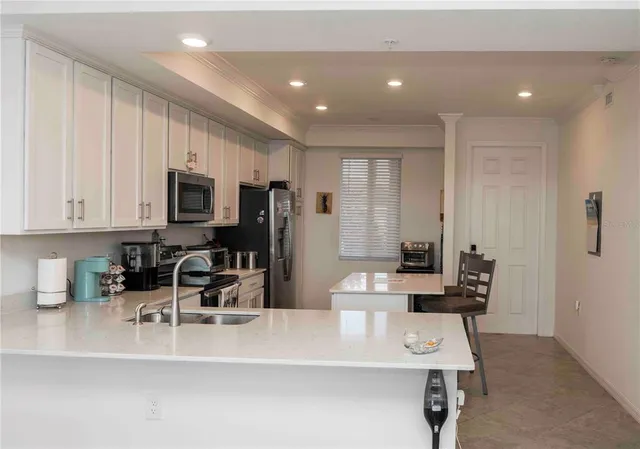 a kitchen with stainless steel appliances a microwave a sink a stove a table and chairs