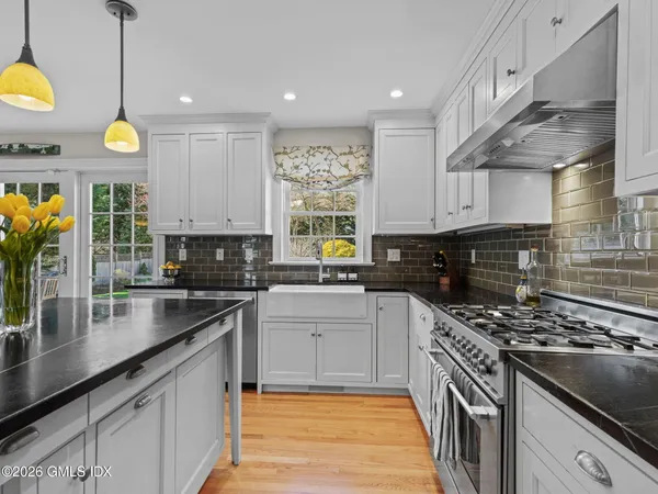 a kitchen with stainless steel appliances granite countertop a sink a stove and cabinets