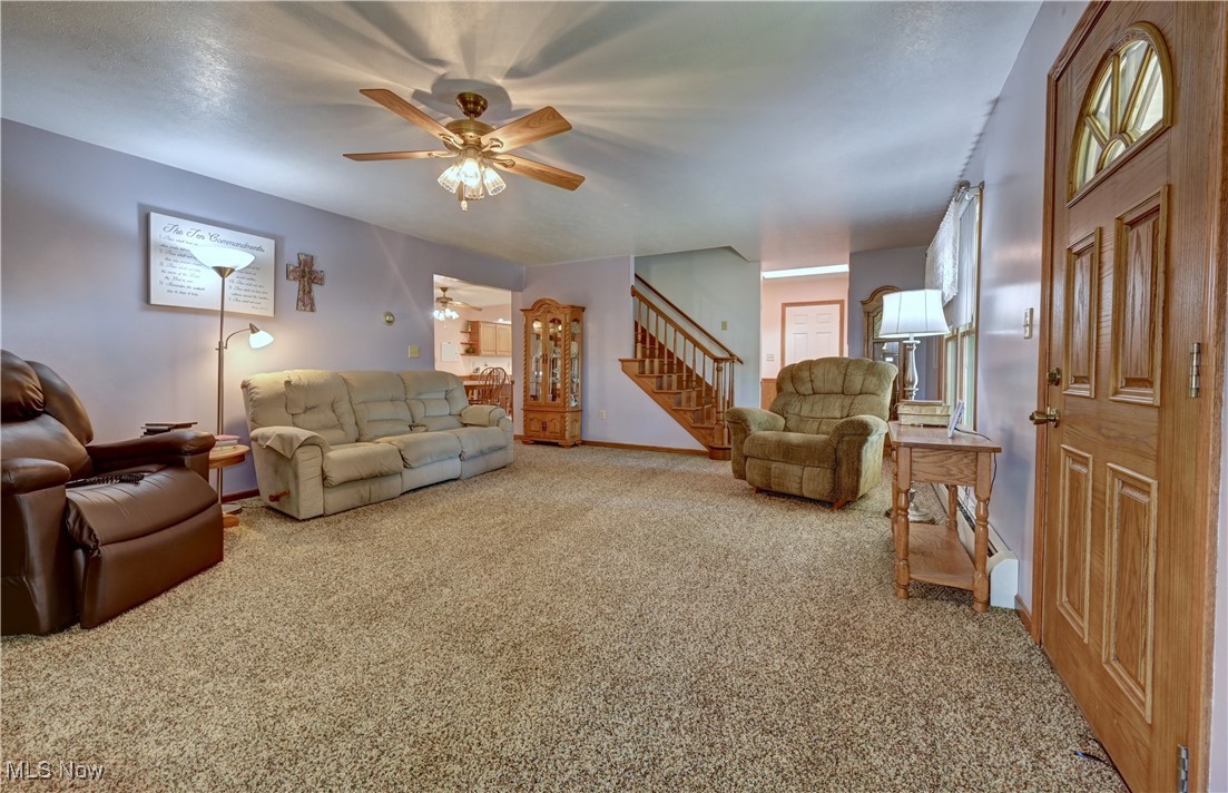 17198 Harrison Road Navarre, OH 44662 - Photo 17 of 45 Carpeted living area with stairs, ceiling fan, and a baseboard radiator
