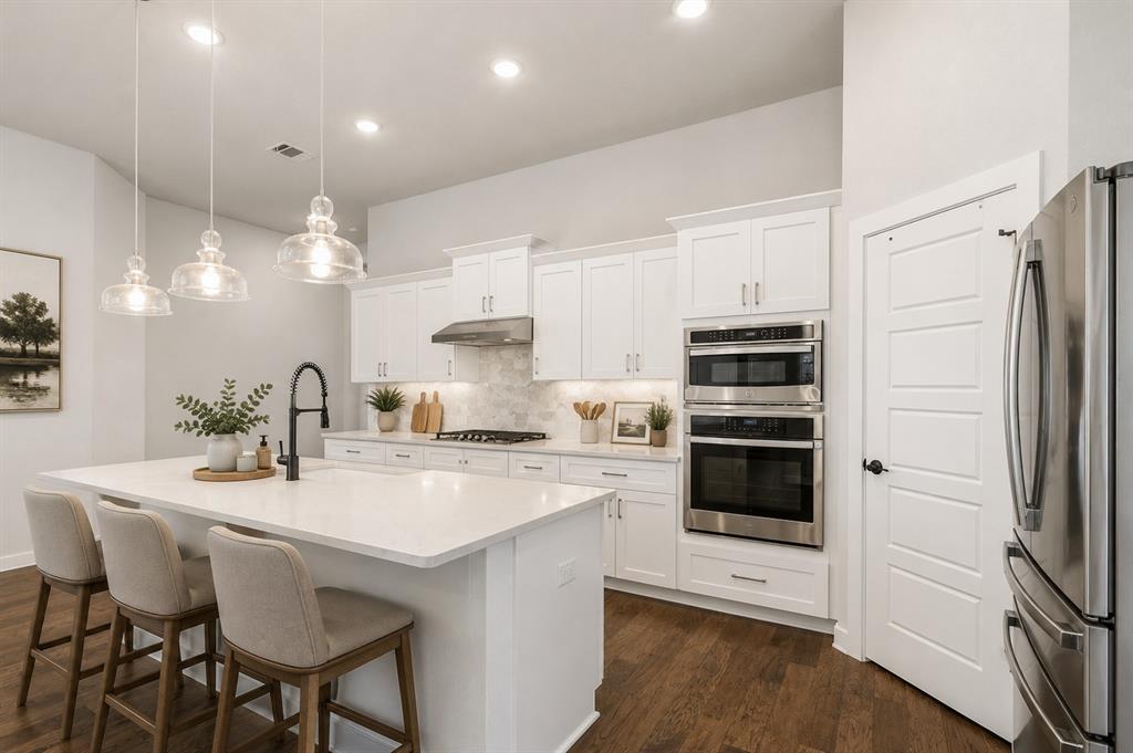 3311 Willena Road Melissa, TX 75454 - Photo 9 of 40 Kitchen featuring white cabinetry, stainless steel appliances including a double oven, a center island with pendant lighting, and wood-finish flooring