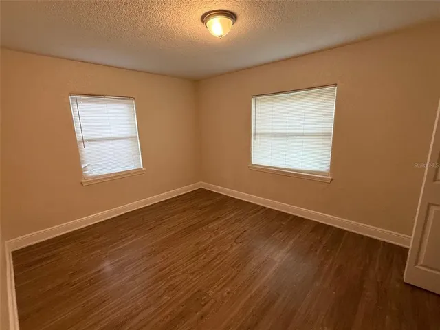 an empty room with wooden floor cabinet and windows