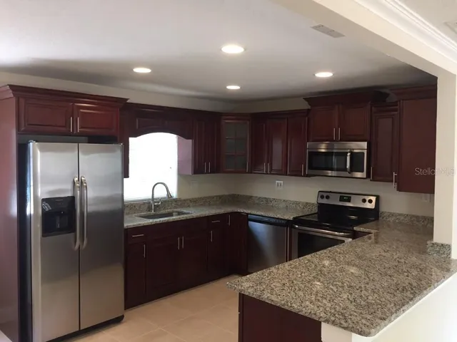 a kitchen with stainless steel appliances granite countertop a sink stove and refrigerator