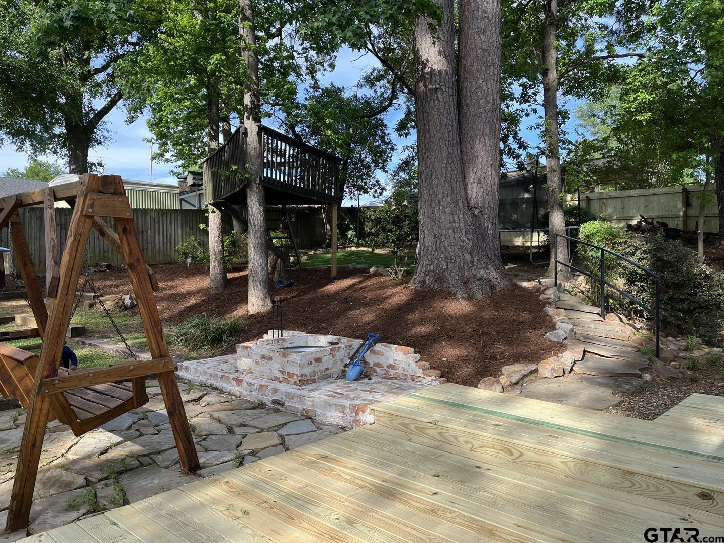 1908 Waunell Drive Tyler, TX 75701 - Photo 34 of 39 a backyard of a house with table and chairs under an large trees