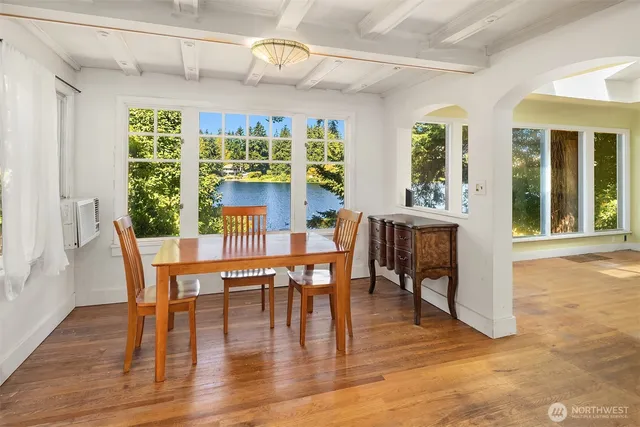a dining room with wooden floor a chandelier a glass table and chairs