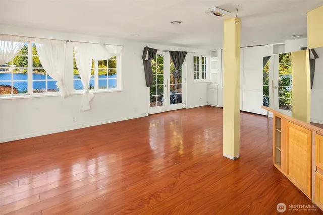 a view of an empty room with wooden floor and a window