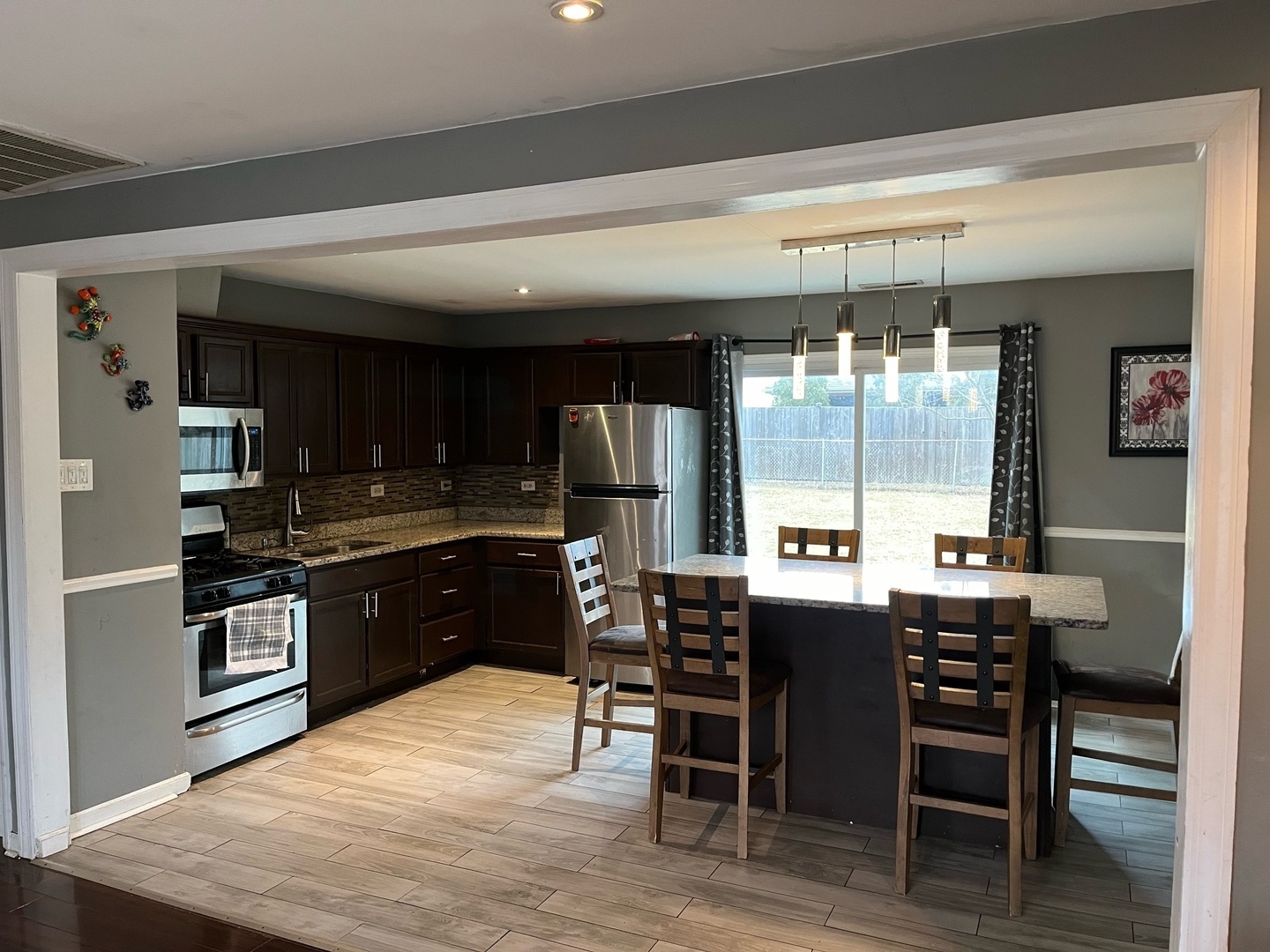 7 Ridge Circle Streamwood, IL 60107 - Photo 3 of 8 a kitchen with stainless steel appliances kitchen island granite countertop a table and chairs in it