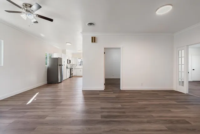 a view of an empty room with wooden floor and a ceiling fan