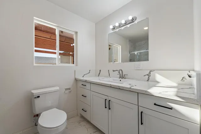 a bathroom with a granite countertop toilet sink and mirror
