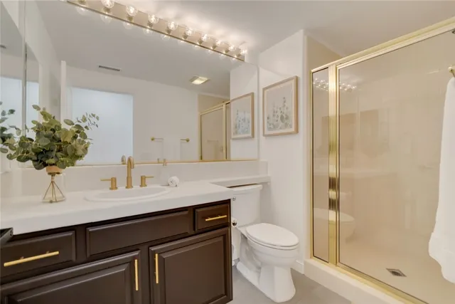 a bathroom with a granite countertop sink a toilet a mirror and shower