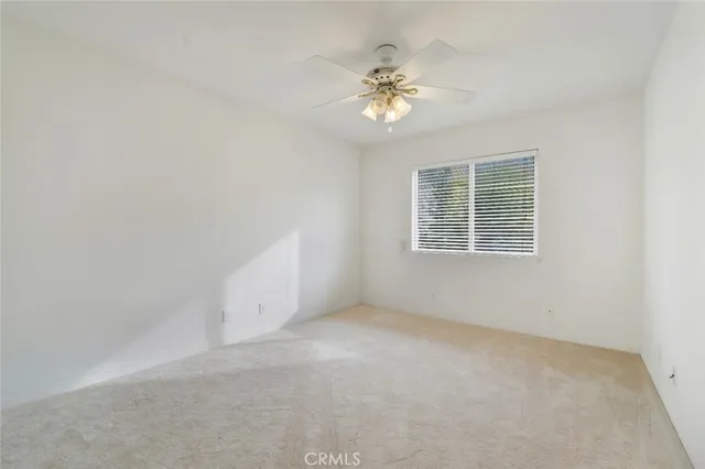 a view of an empty room with chandelier fan