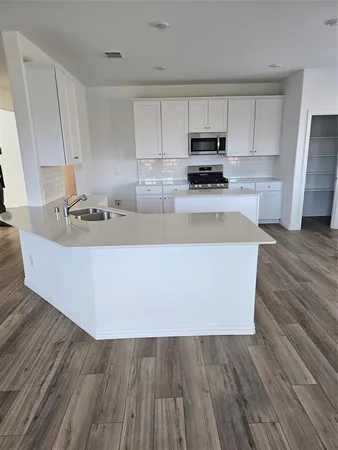 a kitchen with wooden floor and stainless steel appliances